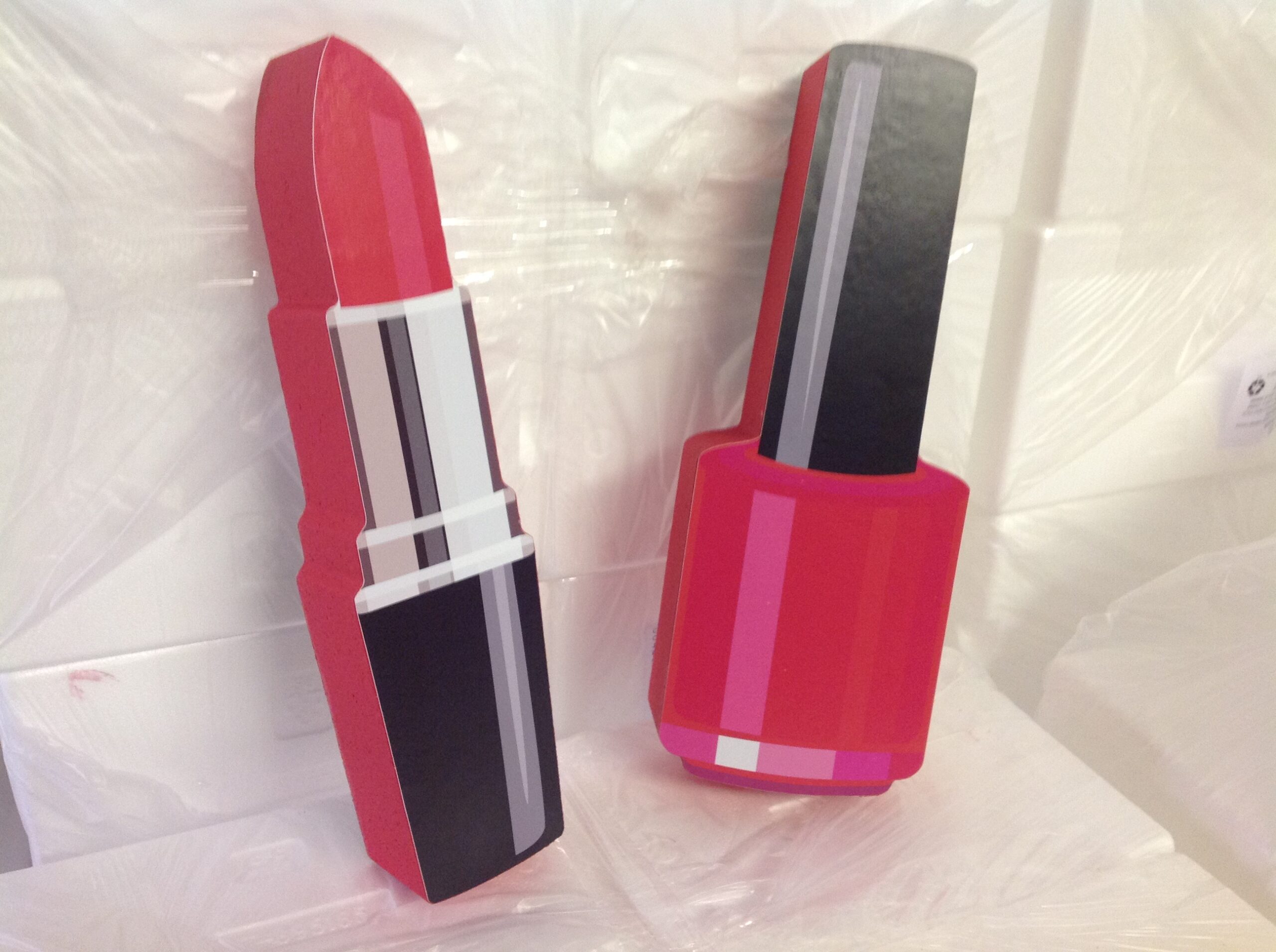 Polystyrene props of lipstick and nail polish bottle staged in workshop