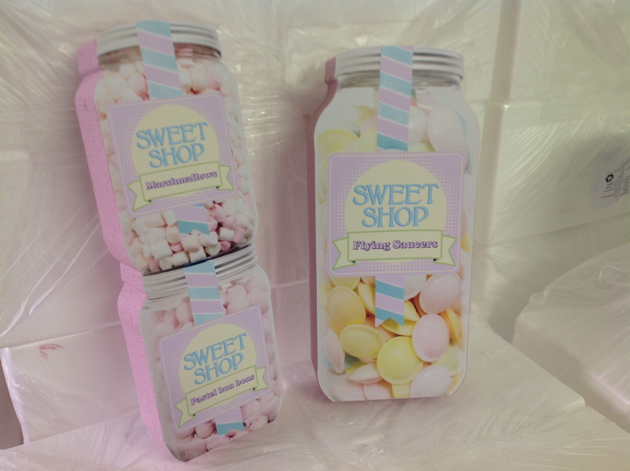 Polystyrene candy jar props labeled SWEET SHOP staged in workshop with wrapped foam blocks